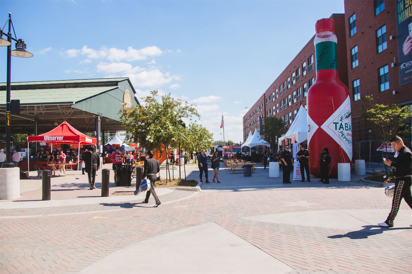 Outdoor plaza at Dallas Farmers Market during Tacolandia — festival tents, a giant Tabasco bottle, and guests filling the open-air space