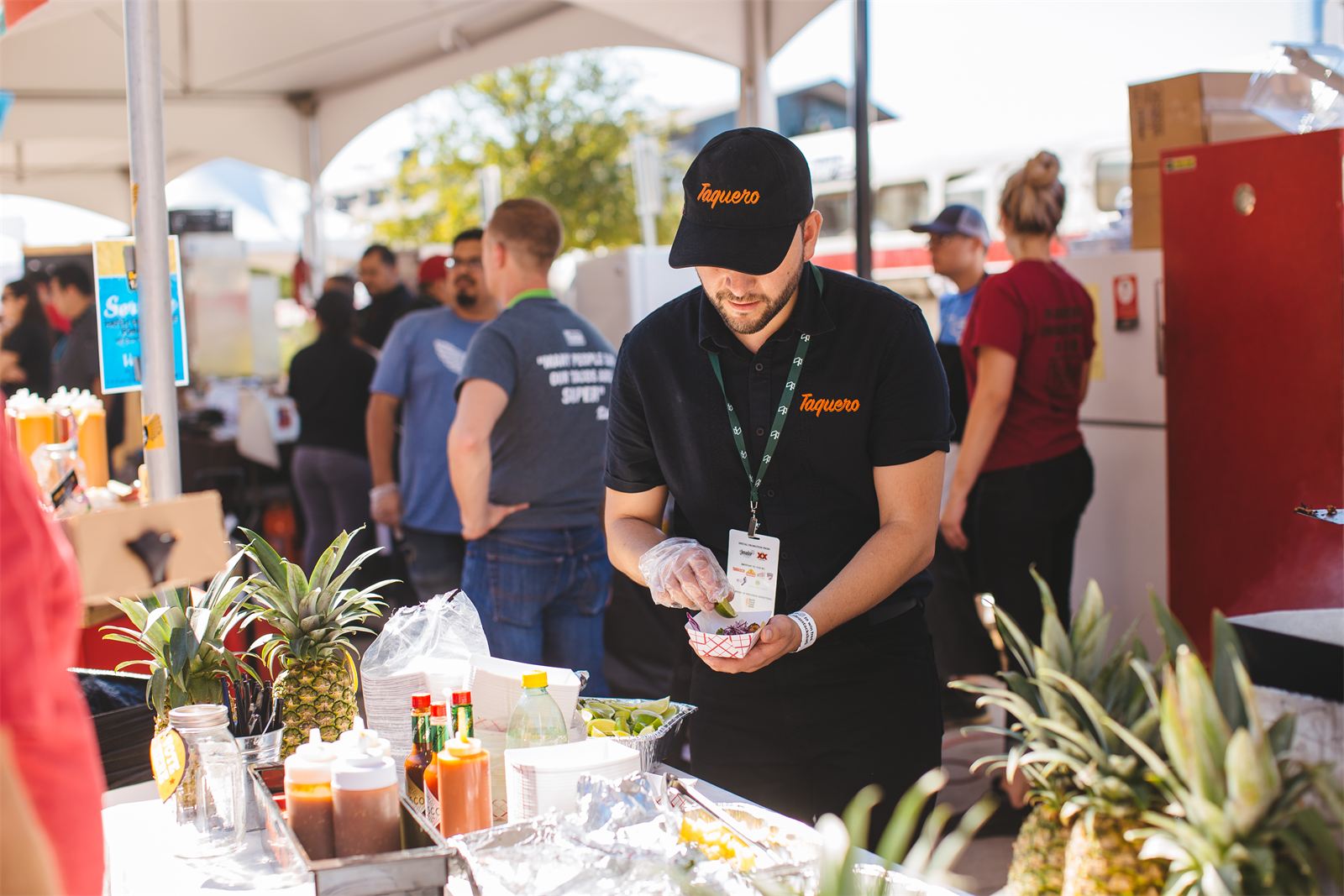 A vendor at a food festival prepares dishes at an outdoor event at Dallas Farmers Market
