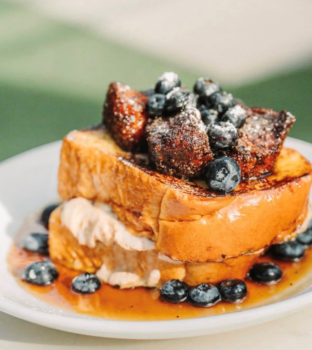 A stack of French toast topped with blueberries and caramelized strawberries from a Market Building vendor